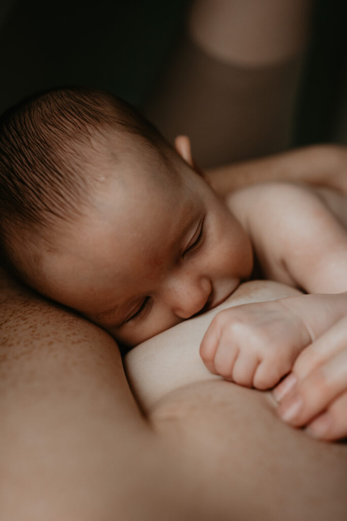 Moeder die borstvoeding geeft tijdens een intieme motherhood shoot