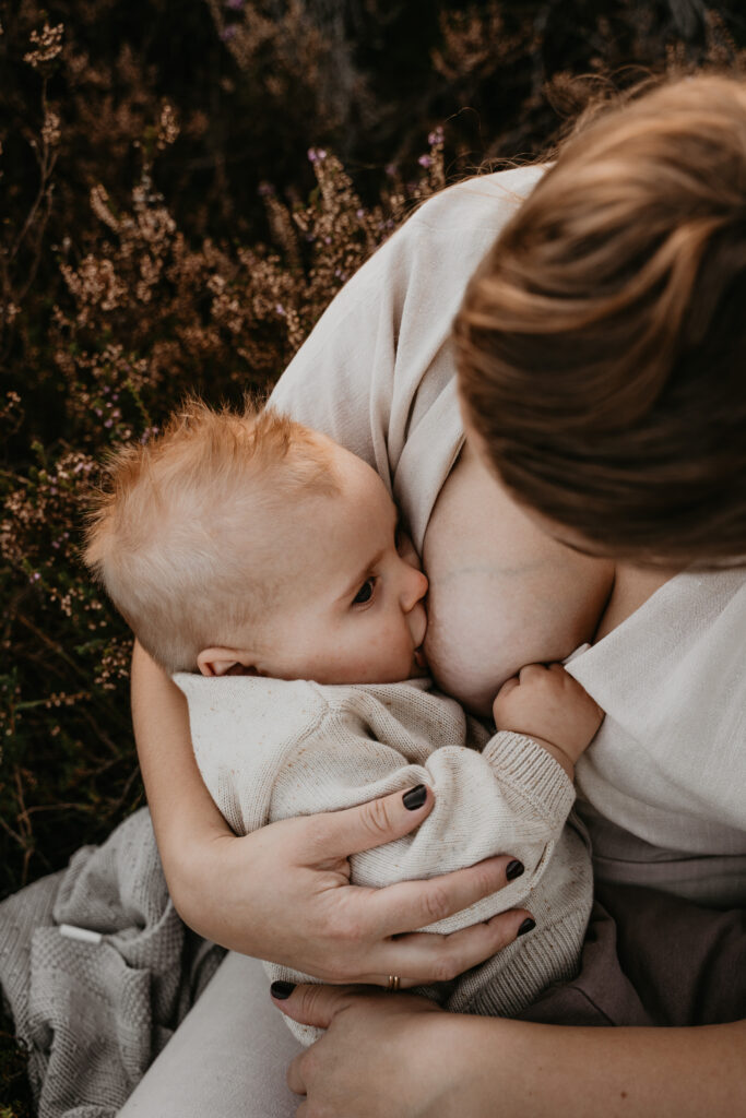 Moeder die borstvoeding geeft tijdens een intieme motherhood shoot