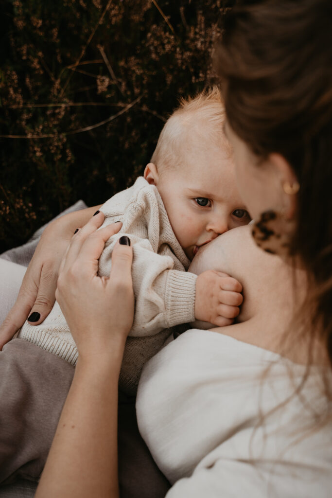 Moeder die borstvoeding geeft tijdens een intieme motherhood shoot